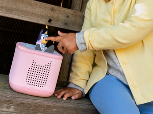 child playing with a pink toniebox 2 and a bluey tonie audio figurine for kids