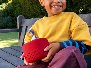 child outside holding a tonie on a Toniebox Lite Cover sunset red on a toniebox lite